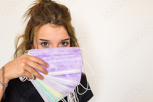 Foto Beautiful brown-eyed girl keeps lot of coloured hygienic masks in hand