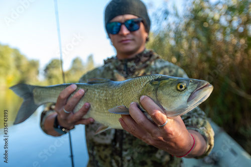 Fisherman holds Asp fish with natural background