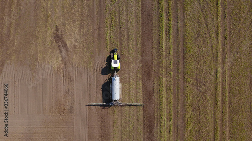 Photography Agriculture: tractor with slurry tanker sprays manure on a field
