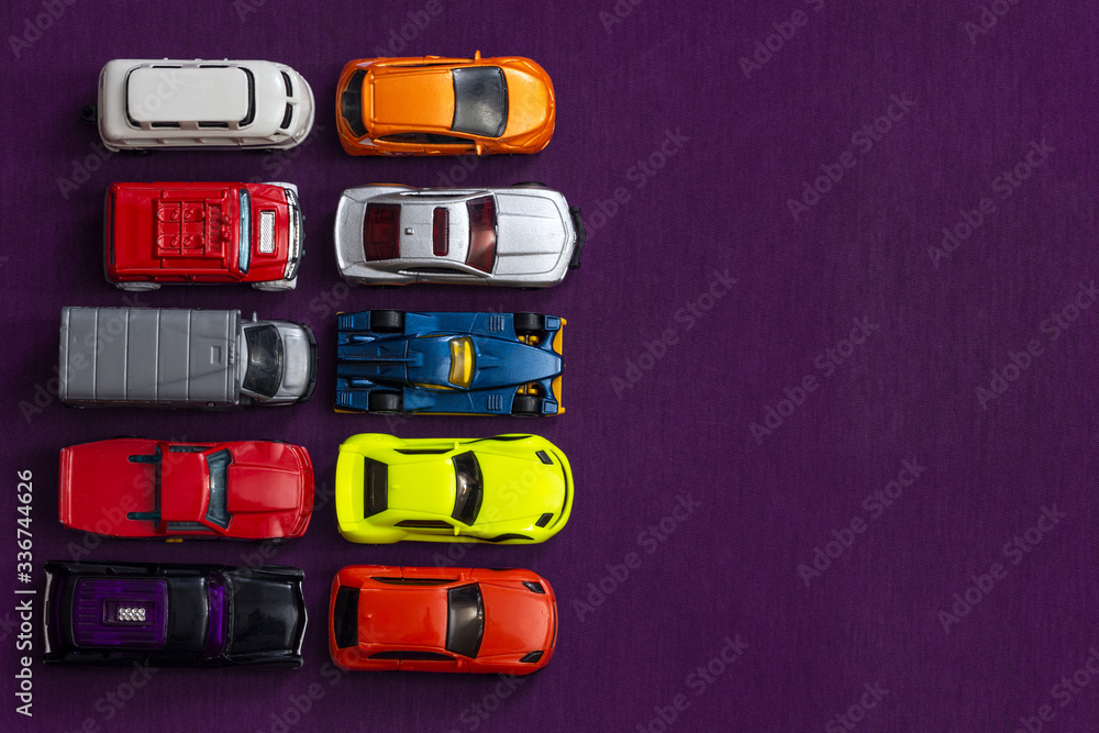 Obraz premium Colorful children's toy cars. Purple background. Bright colors. Automotive business concept. Empty place for text. Flat lay composition. Favorite children's toys.