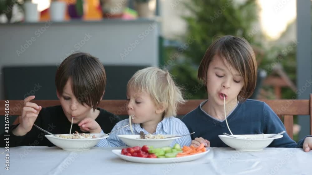 Cute children, boy brothers, eating spaghetti in garden summertime Cute children, boy brothers, eating spaghetti in garden summertime
