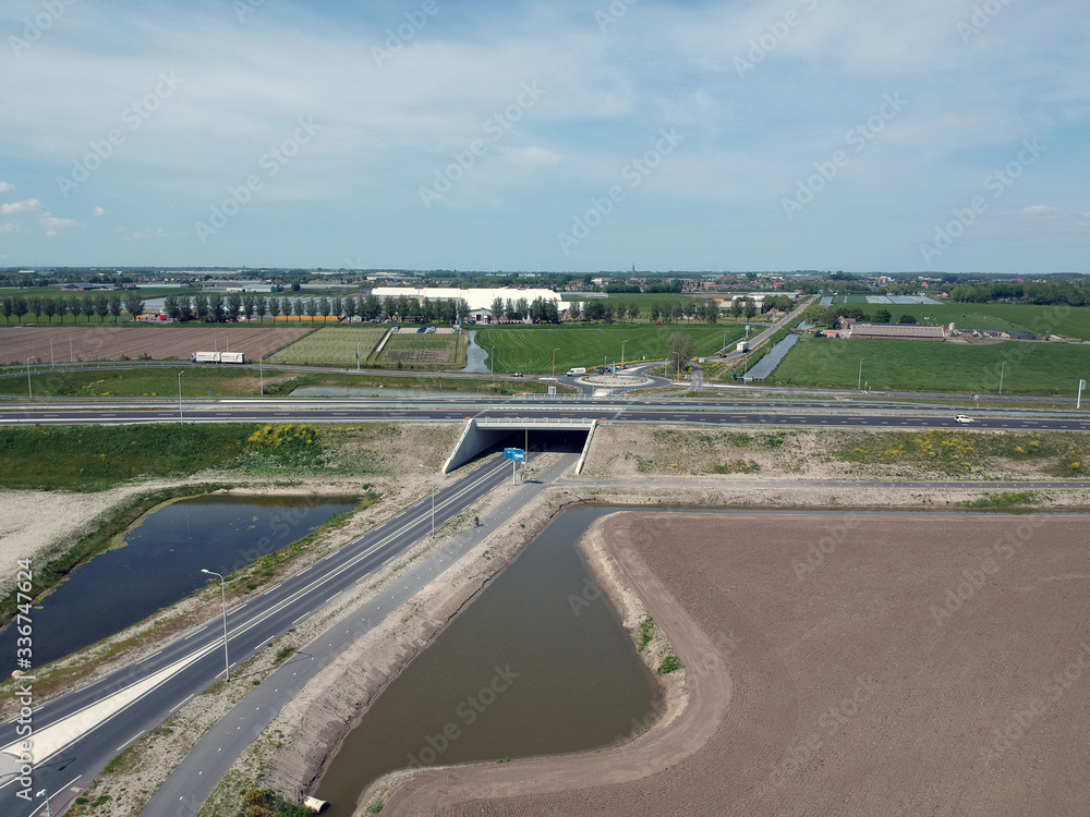 Fototapeta premium Drone photo of a traffic tunnel with motorways and green lawns around it on a beautiful cloudly skyn a beautiful cloudly sky 