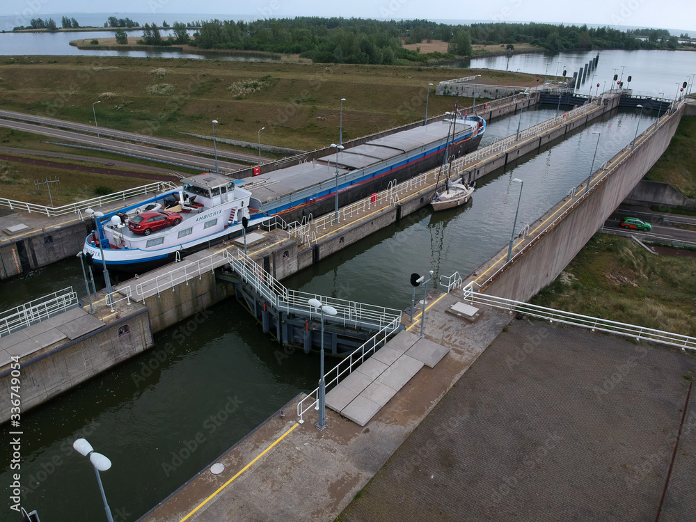 Photograph made with a drone of an Inland navigation vessel in the lock of near enkhuizen, this lock is a naviduct where the traffic passes under the concrete lock