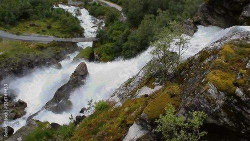 Waterfall and river which is located near path to the Briksdalsbreen (Briksdal) glacier. The melting of this glacier forms waterfall and river with clear water. Jostedalsbreen National Park. Norway. photo