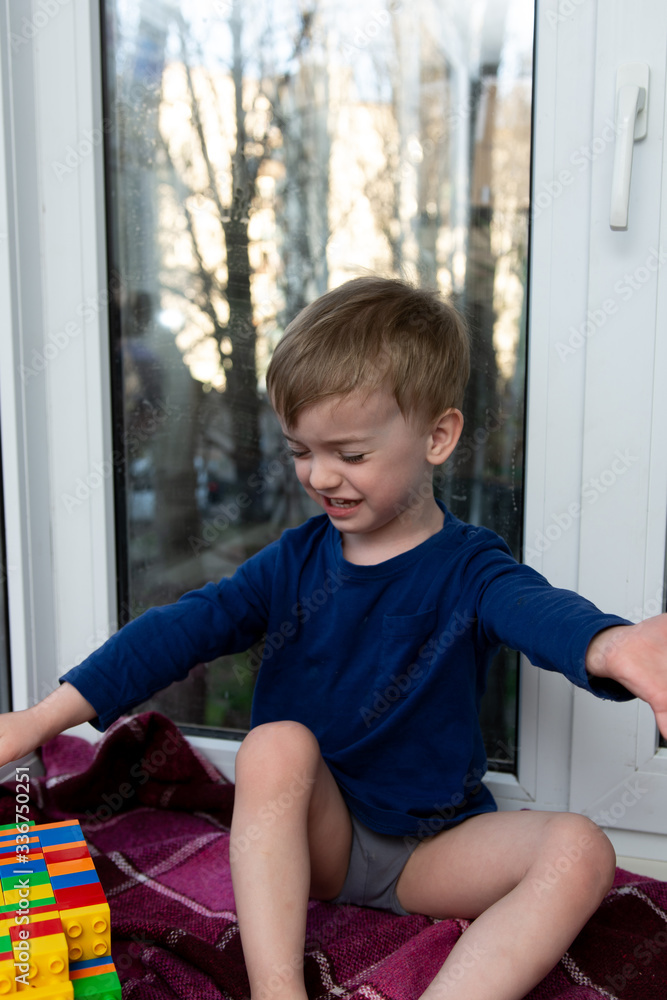 portrait of a crying little boy on the background of a window. portrait of a crying little boy on the background of a window.