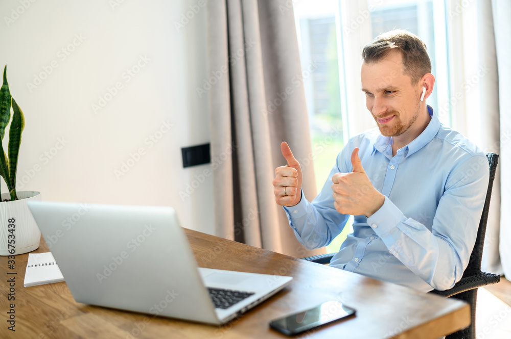 Guy in a formal shirt with airpods uses a laptop Guy in a formal shirt with airpods uses a laptop