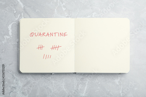 Open notebook on marble table, top view. Counting days of quarantine during coronavirus outbreak