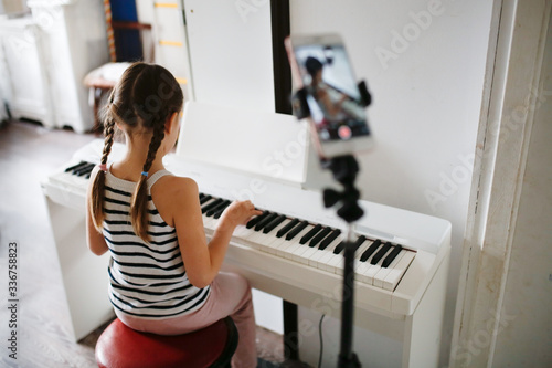 child plays digital piano and records video phone photo