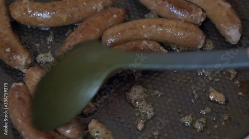 Grill Tongs flipping Sausages on a sizzling hot grill plate