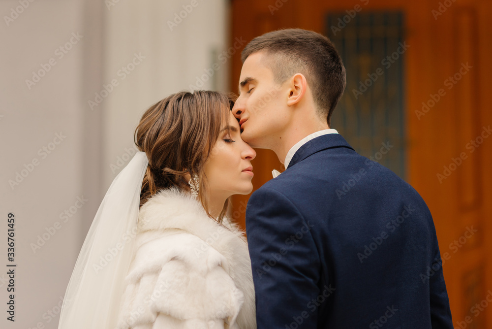 Groom elegantly kisses the bride on the forehead. Wedding photography of stylish newlyweds. Close-up portrait. Groom elegantly kisses the bride on the forehead. Wedding photography of stylish newlyweds. Close-up portrait.