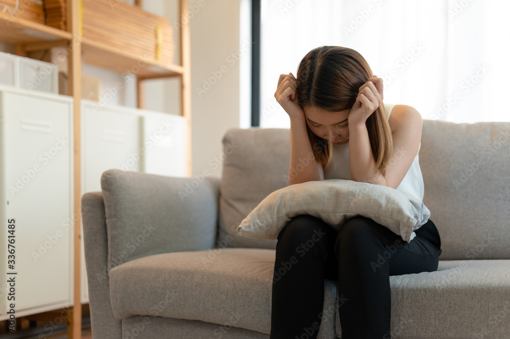 Depression and sadness concept,Young asian woman covering her face sitting on sofa in home. Depression and sadness concept,Young asian woman covering her face sitting on sofa in home.