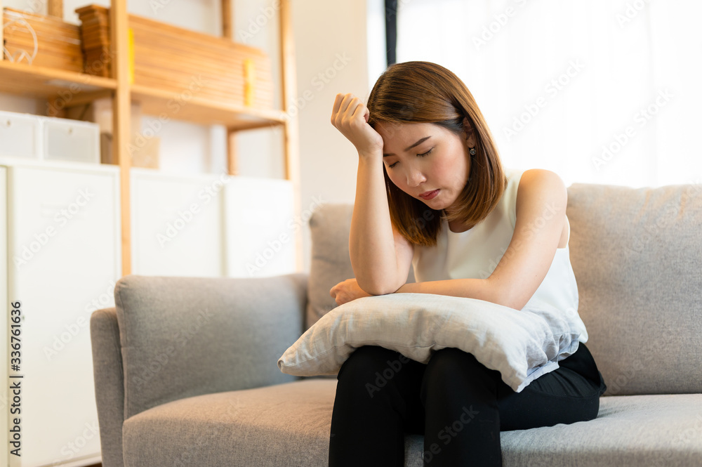 Depression and sadness concept,Young asian woman covering her face sitting on sofa in home. Depression and sadness concept,Young asian woman covering her face sitting on sofa in home.