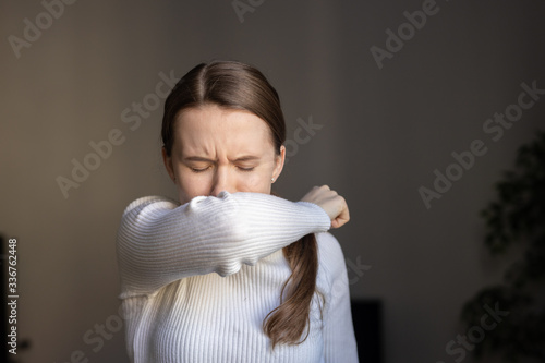 Cough in tissue covering nose and mouth when coughing. European woman sick with flu at home.