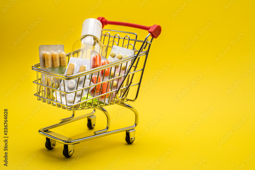 Miniature shopping trolley with medicines, antiseptic. Self-isolation. Yellow background. Miniature shopping trolley with medicines, antiseptic. Self-isolation. Yellow background.