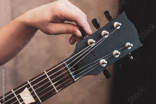 guy tuning his guitar. Guitar neck and tuning pegs