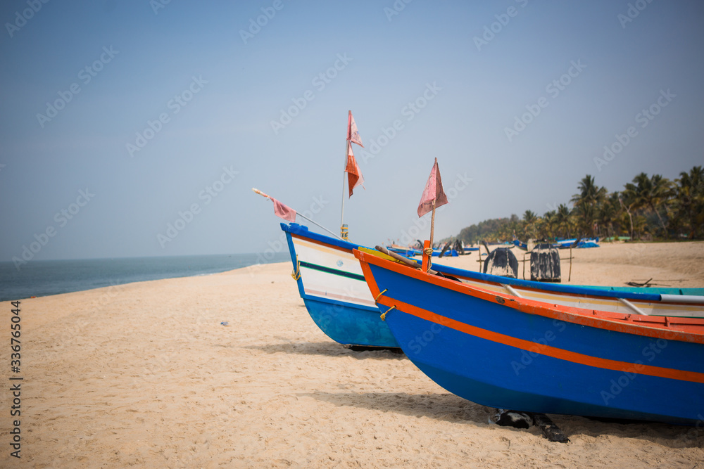 Fishing boat of Indian fishermen on the sandy beach in Kerala, fishing village Mararikulam. Bright colorful boat among palm trees Fishing boat of Indian fishermen on the sandy beach in Kerala, fishing village Mararikulam. Bright colorful boat among palm trees