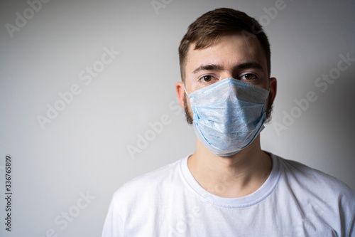 A bearded man in a medical mask looks at the camera. Self isolation