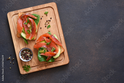 Toast with avocado and salmon on a blackboard on a concrete background.