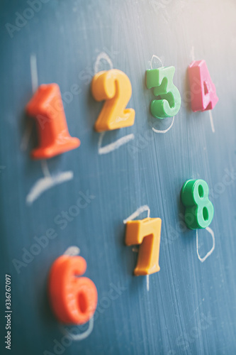 Learning numbers on a blackboard with colorful magnets and handwriting on blackboard during homeschooling at quarantine