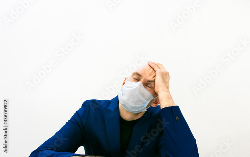 Male person holds his head with left hand and closed eyes showing tiredness, Business and doctors frustration concept.