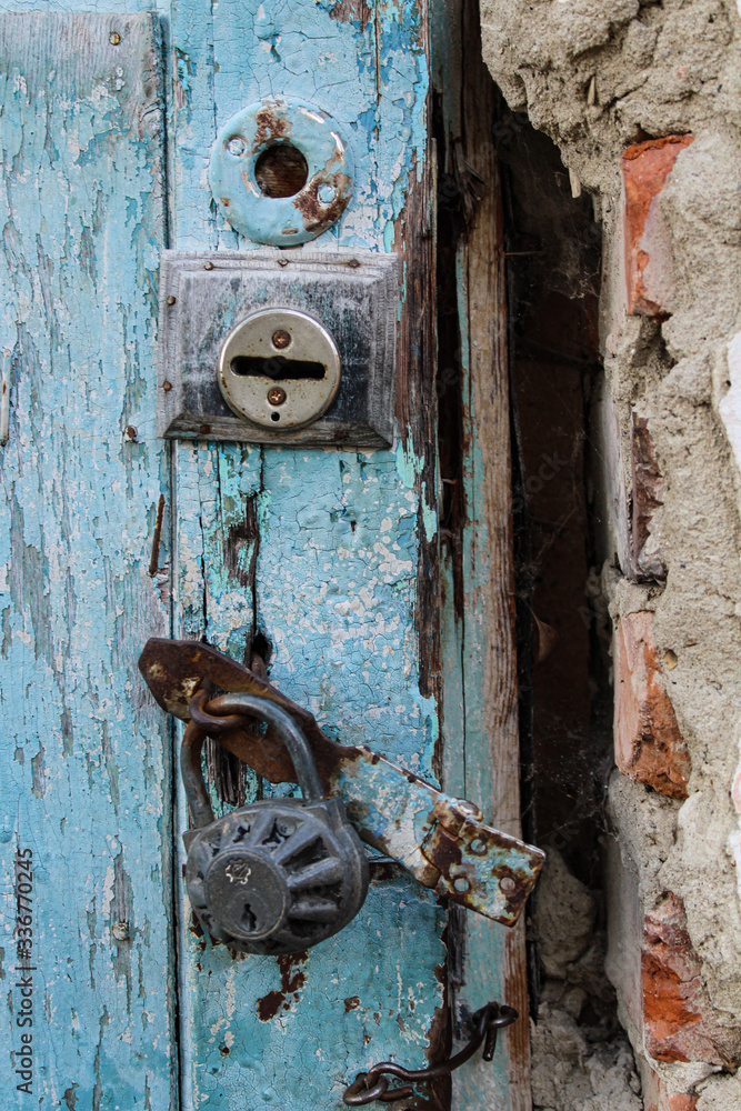 Old, rusty, iron, padlock on a wooden door. Locked. Forgotten. Outdated. Ancient. Decrepit. Closed.