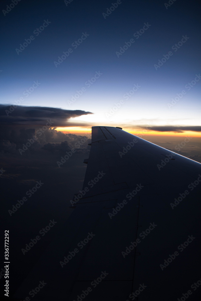 cloudy sunset sky over plane wing with thunderhead