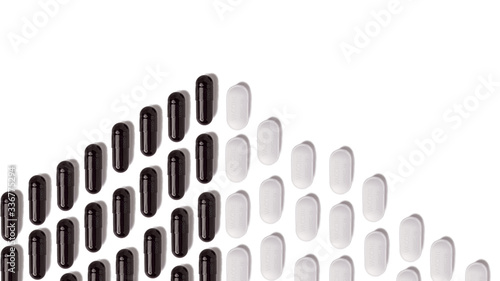 Top view of many white and black pills isolated on white background.