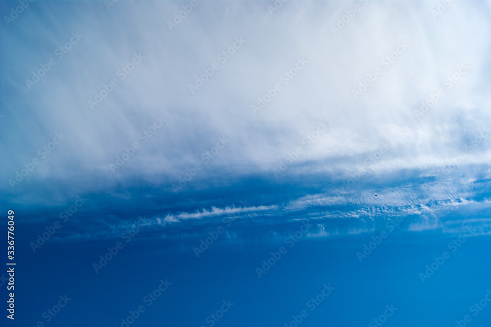 Fototapeta premium Contrast of smooth blue saturated sky and soft loose white clouds. Sky photo