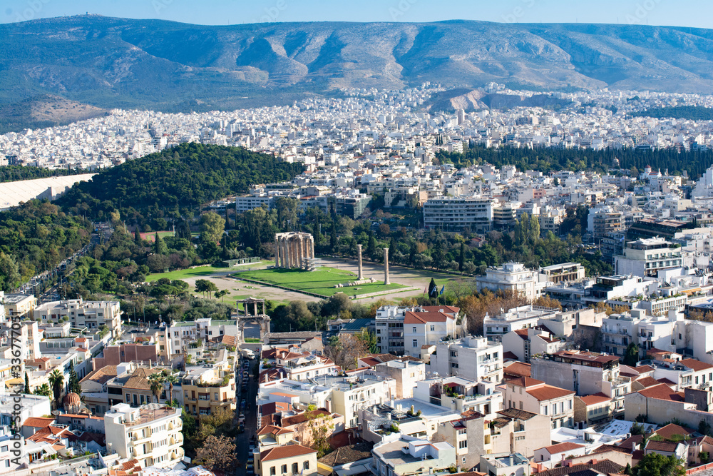 view of the city of Athens with the ruins of the temple of zeus olympic with mountains on background