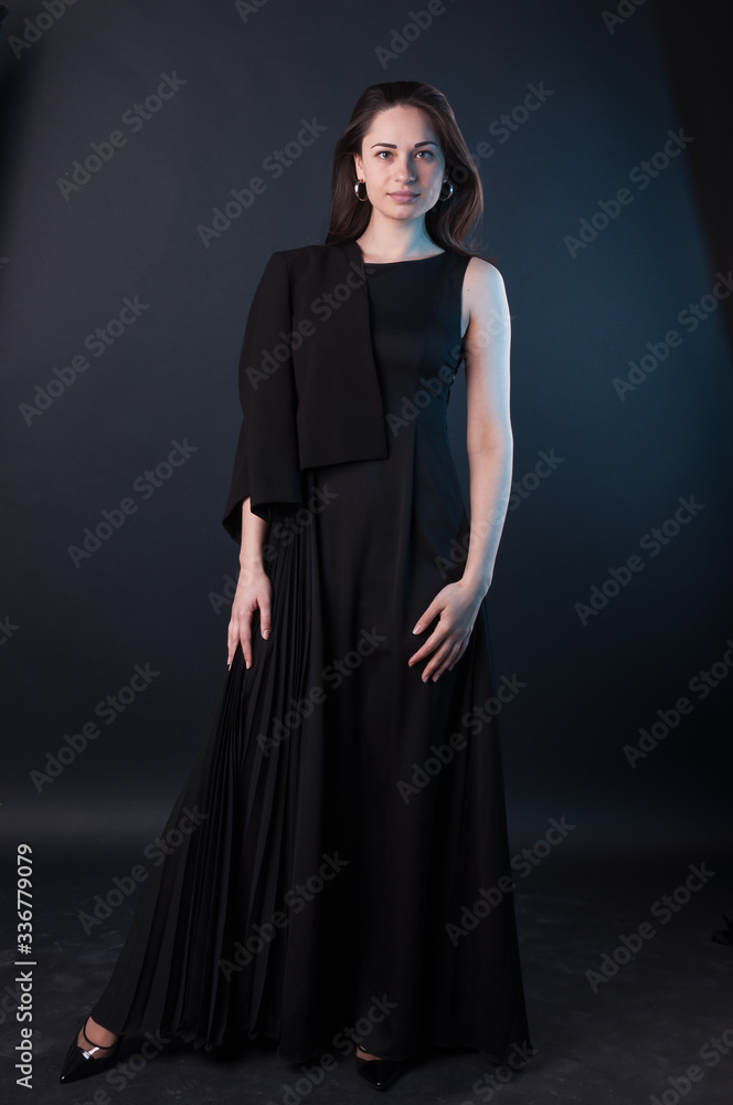 Young attractive beautiful girl is posing in the dark. Elegant black dress, so dark everywhere. Amazing girl with attractive appearance Young attractive beautiful girl is posing in the dark. Elegant black dress, so dark everywhere. Amazing girl with attractive appearance