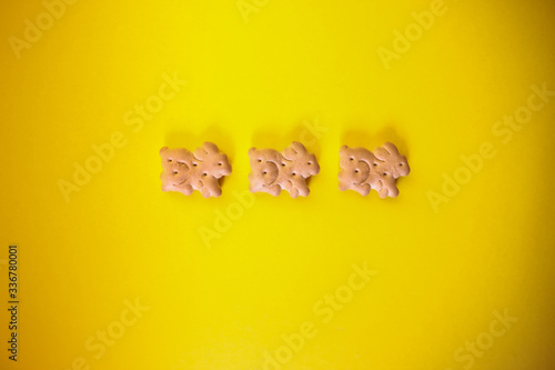 Fototapeta Naklejka Na Ścianę i Meble -  three cute easter bunny cookies on yellow background, bright and vibrant easter backdrop, top view