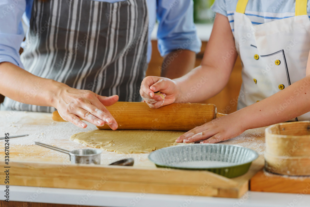 Mother and daughter making apple pie in the kitchen. Teaching child to help at home Mother and daughter making apple pie in the kitchen. Teaching child to help at home