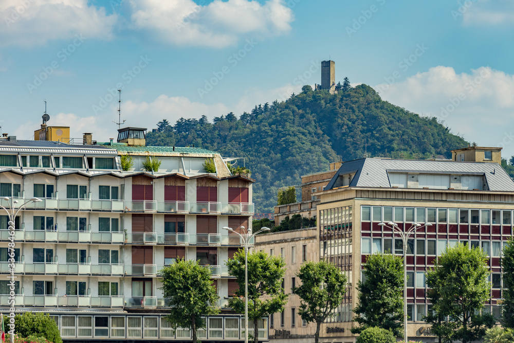 Como, ITALY - August 4, 2019: Apartments, villas, hotels near Lake Como. Beautiful Italian Como city. Baradello Castle on the background. Warm sunny summer day in very popular holiday destination