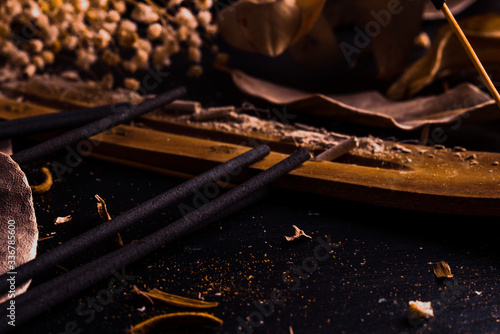 Stick holder and incense stick with leaves and flowers on black background