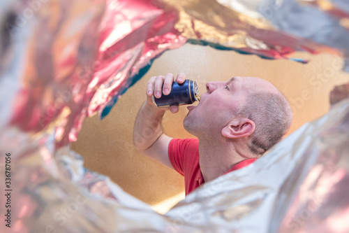 A man with a short haircut drinks a drink, beer, juice from a can. A man with a very open mouth. Emotions on the face. Bright orange background. beer festival oktobrfest. photo