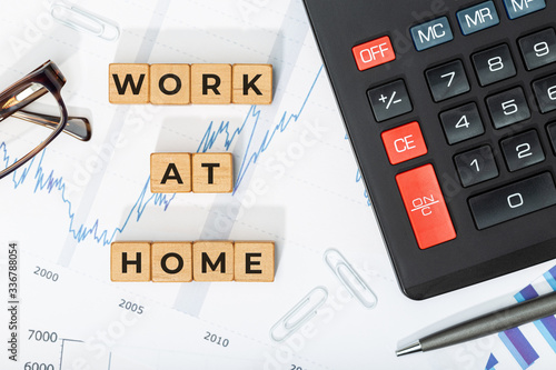 Work at home concept. Wooden blocks with phrase, calculator and printed charts. Business background