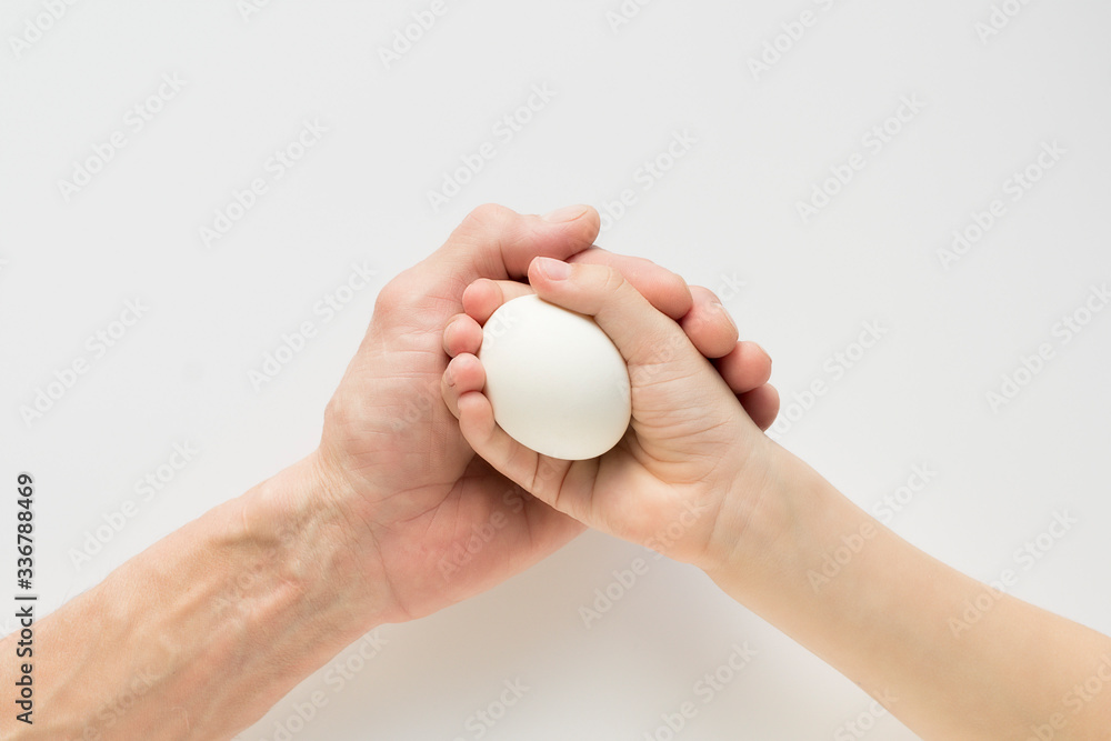 Hand of a child and an adult holding an egg Hand of a child and an adult holding an egg
