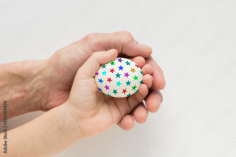 Hand of a child and an adult holding an Easter egg Hand of a child and an adult holding an Easter egg