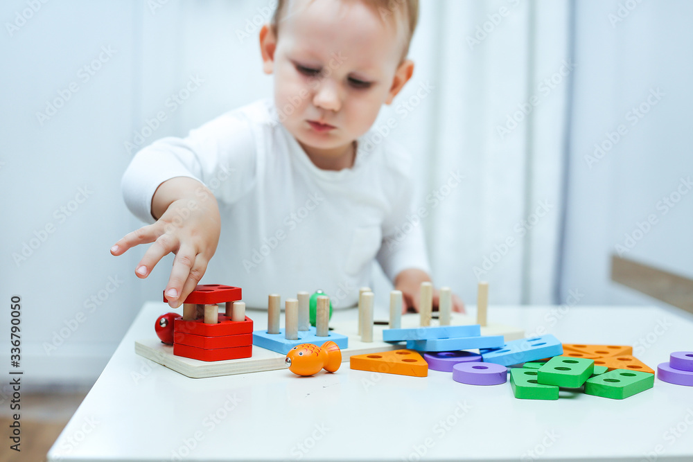 baby boy plays with educational toy. toddler play with a wooden toys at home. Toddler play with a color educational toy. Child play at the table in the baby room. Child development. baby boy plays with educational toy. toddler play with a wooden toys at home. Toddler play with a color educational toy. Child play at the table in the baby room. Child development.