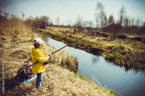 Fisherman child holds fishing rod with reel in his hand on fishing
