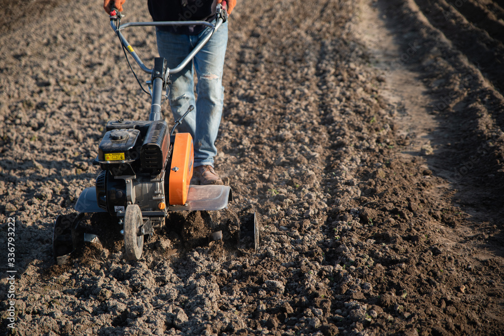 small plowing machine in hands of a farmer making arable in black soil small plowing machine in hands of a farmer making arable in black soil