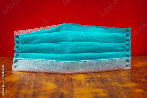 close up view of medical face mask on table against red background