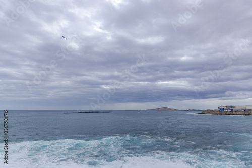 Ocean coast time-lapse during afternoon day with fast moving bright clouds moving sea and taking off planes from Gran Canary Island International Airport. photo