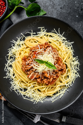 Spaghetti bolognese pasta with tomato and minced meat, parmesan cheese and basil. Black background. Top view