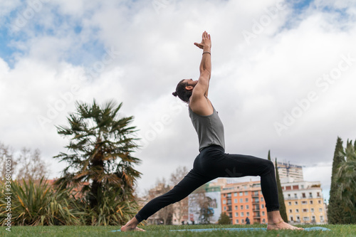 young man with ponytail doing yoga in a park