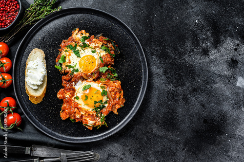 Traditional Israeli Cuisine dishes Shakshuka. Fried egg with tomatoes and paprika. Black background. Top view. Copy space
