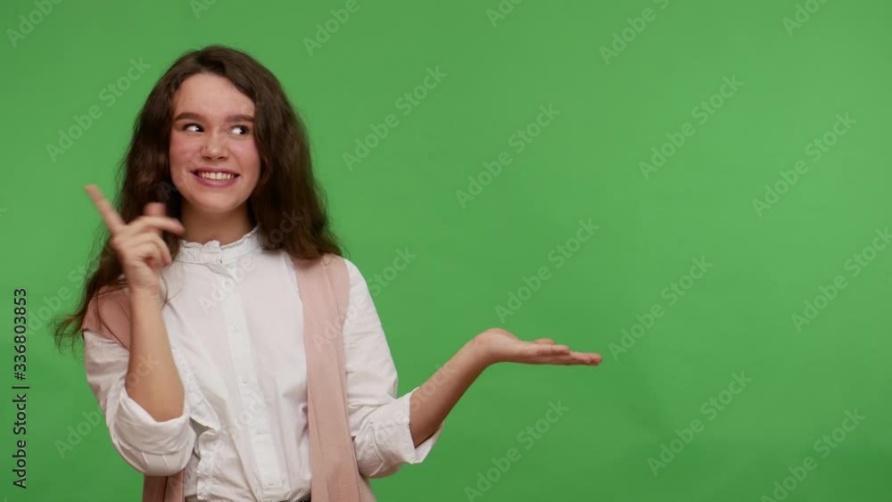 Product advertising! Happy amazed teenage girl holding copy space on palm for promotional content, showing empty place for commercial text, workspace mock up. studio shot isolated on green background Product advertising! Happy amazed teenage girl holding copy space on palm for promotional content, showing empty place for commercial text, workspace mock up. studio shot isolated on green background