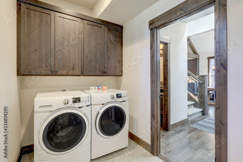 Laundry room with white wahser and dryer and dark brown wood cabinets.