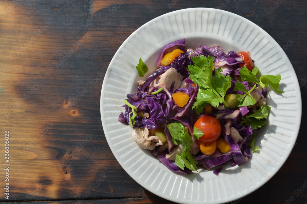 fresh salad purple color with chicken and green vegetables in white bowl on the black  wooden table
