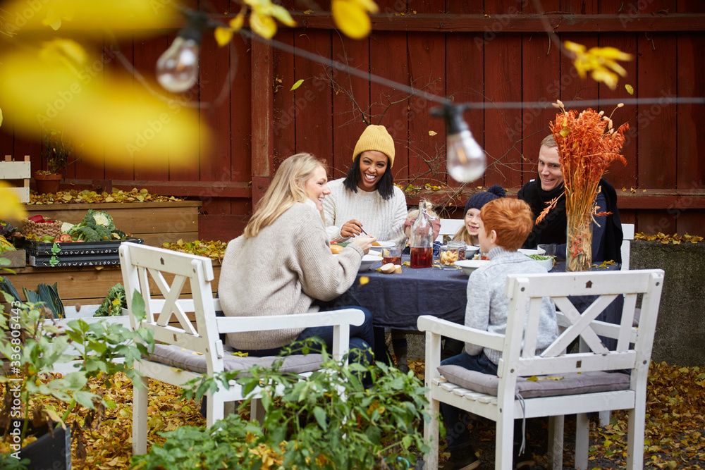 Smiling family and friends sitting at table for social gathering Smiling family and friends sitting at table for social gathering